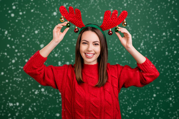 Wall Mural - Photo of young girl happy positive smile touch balls reindeer horns holiday christmas decor isolated over green color background