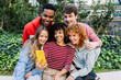 © Xavier Lorenzo - Young multiracial group of teenage student friends watching social media content on mobile phone app at city street. Youth and technology lifestyle concept