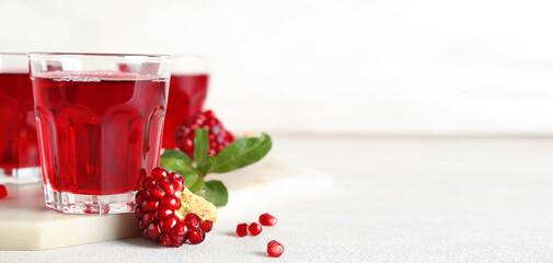 Wall Mural - Glasses of fresh pomegranate juice on light background