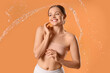 © Pixel-Shot - Happy young woman with splash of water on orange background