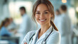 © 沈军 贡 - A beautiful female doctor smiling with her arms crossed in front of blurred medical staff