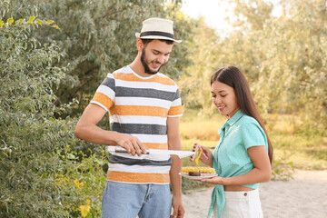 Wall Mural - Young couple cooking food on grill at barbeque party