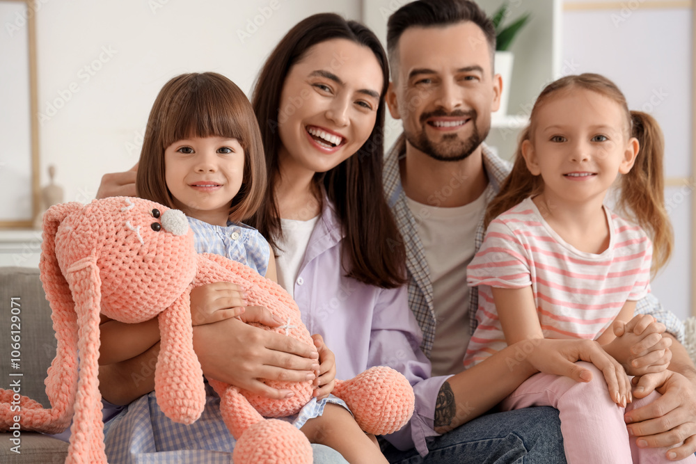 Happy family with toy rabbit sitting on sofa at home