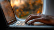 © ClicksdeMexico - A person is typing on a laptop computer with a view of the outside