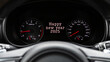 © Виталий Сова - Close up Instrument automobile panel with Odometer, speedometer, tachometer, fuel level, which says Happy New Year 2025. The concept of the new year and Christmas in the automotive field.