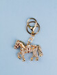 © Виталий Сова - Close up of bright metal horse  keychain with rhinestones   on blue  background