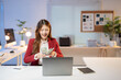 © Tj - Young businesswoman sitting at her desk counting us dollar banknotes and smiling, enjoying her financial success in the office