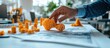 © GoDress - A hand reaches out to pick up a small orange 3D printed model on a white table, surrounded by other smaller models.