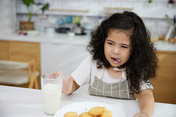 portrait child girl drinking fresh milk and enjoy eating cookies in the kitchen