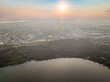 Big lake with green shores in bright sun light and city on horizon, aerial landscape. Recreation concept. Aerial view