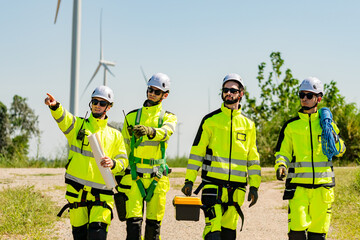 Four young male wind farm engineers work inspecting field systems.Wind turbine engineer inspection and wind turbine inspection progress at construction site.