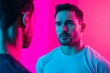 © Siripong - Intense moment captured between two men in vibrant pink and blue lights, showcasing emotion and connection.