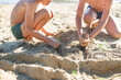 © Olga Gimaeva - Two boys brothers playing on a sandy beach on summer vacation. A children are building a sand castle on the sea.