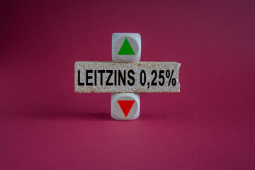 Leitzins 0.25 percent symbol. A wooden cubes with up arrow. Brick block with the concept German expression Leitzins 0.25 percent - key interest rate 0.25 percent. Beautiful red background.