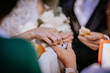 © Raivo - Close-up of a bride dipping bread into a small salt dish during a traditional wedding ritual, surrounded by hands of family members.
