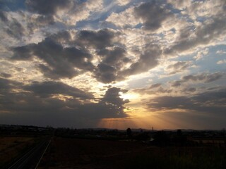 Sticker - Countryside landscape with a dramatic cloudy sky and sunbeams penetrating through clouds