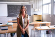 © CarlosBarquero - Portrait middle-aged female high school teacher looking smiling at camera with joined hands in classroom. Happy grey-haired science tutor Caucasian woman posing joyful leaning on desk in empty class