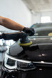 © alones - Professional Man with a polishing machine polishes a black car hood in a detailing center. Car care and scratch removal. Car shine