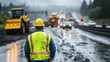 © Maksym - On a busy highway construction site, a worker in protective gear surveys the scene, with bulldozers and cement mixers operating in the background, highlighting the organization and