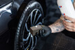 © alones - Professional man washing car and wheels in garage. Detailing. Tire care