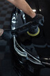 © alones - Professional man with polishing tool polishing black car in garage . Detailing. Varnish care and scratch removal