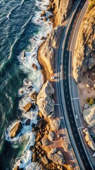 Aerial view of a coastal road winding along rocky cliffs, showcasing the dynamic interaction between land and sea under a clear sky.