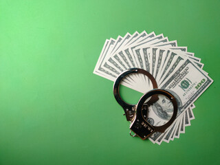 Top view banknotes and metal hand cuff on a green background