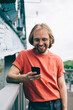© BullRun - Laughing man in red t shirt surfing smartphone
