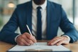 © Vilaysack - Businessman in Suit Signing Document at Desk