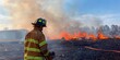 © DC Stocker - A firefighter stands amidst a raging wildfire, surrounded by flames and smoke, ready to tackle the emergency.