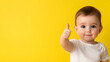 © Ajmeer - a toddler giving a thumbs up on yellow background