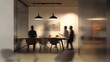 © Mohammed - A group of people blurred as they sit around a table in a modern office space. The sleek, minimalist design features a wooden table with black chairs and three pendant lights.