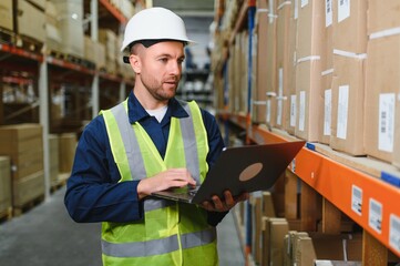 Worker with laptop computer in mail order warehouse