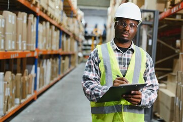 African american warehouseman with clipboard checking delivery, stock in warehouse