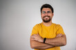 © Nenad - Portrait of happy fashionable handsome man in yellow t-shirt and glasses crossing hands and smiling. Photo of a happy young casual man standing. Caucasian handsome man isolated on grey background