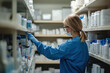 © KirKam - Woman in blue jacket and glasses examining shelf of medications.