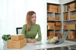 © Treerat - A woman is sitting at a desk with a laptop and a pen
