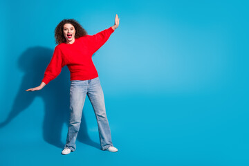 Full body photo of attractive young woman hold push empty space dressed stylish red clothes isolated on blue color background