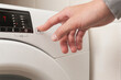 © OR MIXphoto - A person is pressing a button on a white washing machine