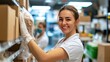 © Lens Legacy - A woman in a white apron smiles while organizing supplies on shelves in a warehouse setting, suggesting efficiency, positivity, and teamwork in the workplace.