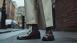 © Fana Art - Close-up of a man's feet wearing brown leather shoes and beige pants standing on a city street.