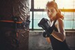 © darshika - Indian asian young woman boxing in gym with punching bag with gloves on