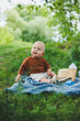 © DSMT - A 1-year-old boy sits on the grass and drinks water. A walk of the baby in the fresh air in the summer. Picnic for a child.