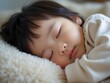 © Bianca - Close-up of an Asian baby peacefully sleeping on a soft, fluffy blanket indoors, capturing innocence and warmth in a cozy environment