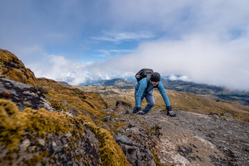 young man climbing hiking a mountain, winning in hiking reaching life golas, success, freedom and toughness