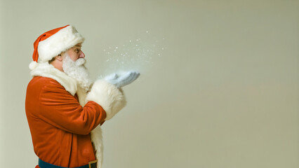 Side view portrait of classic Santa Claus blowing snow while standing against isolated background, copy space