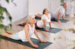 © JackF - Mature women of different year practice yoga and Pilates in virabhadrasana pose in the gym