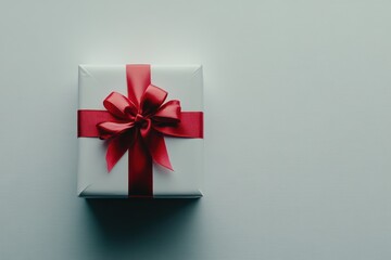 Wall Mural - A white gift box with a red ribbon bow, set against a clean background for simplicity.