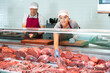 © JackF - Adult man and young woman butchers in aprons put raw meat beef in butcher shop window