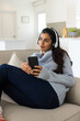 © Wavebreak Media - Relaxing at home, woman listening to music on headphones with smartphone